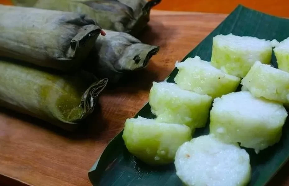 Potongan lontong yang sangat padat, halus, dan berwarna hijau zaitun di atas daun pisang.