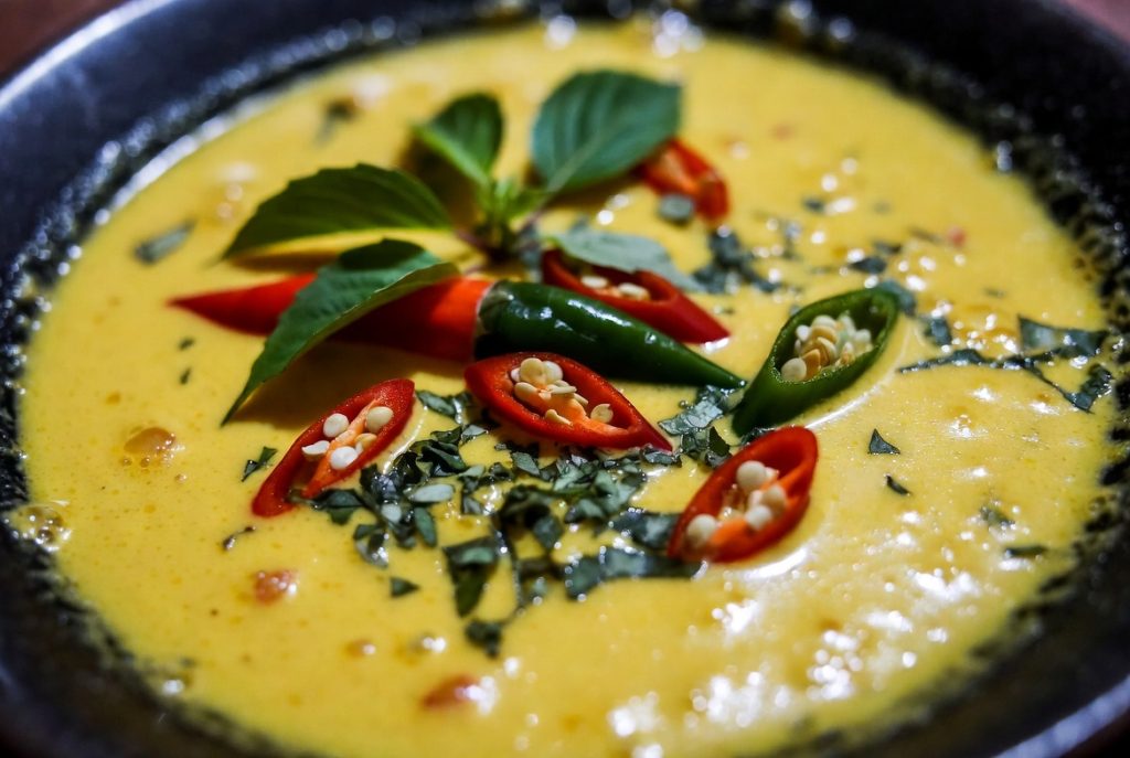 Close-up Paniki santan pedas dengan kuah kuning kental dan daun kemangi segar